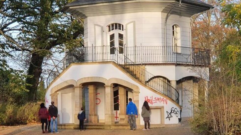 Spaziergänger stehen vorm beschmierten Teehaus. © privat