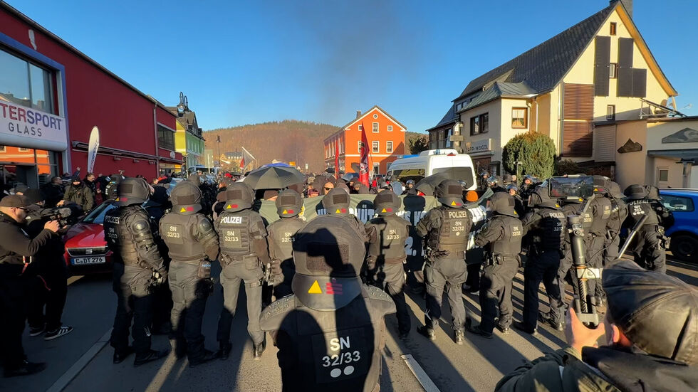 Polizisten und Demonstranten stehen sich gegenüber. Im Hintergrund ist Rauch zu sehen.