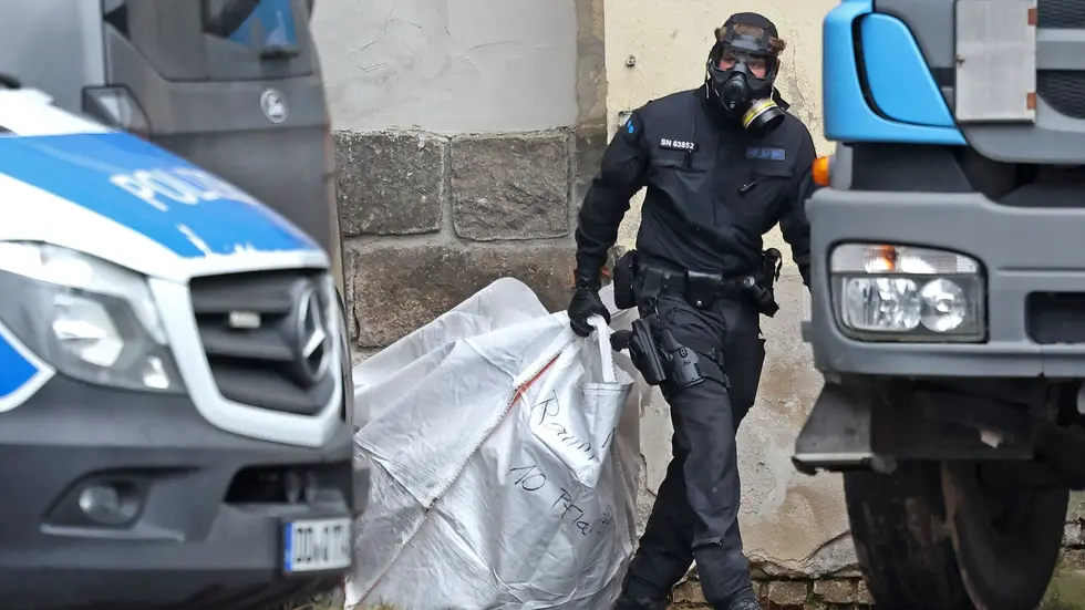 Ein Beamter schleppt einen Sack mit Cannabispflanzen aus dem Gebäude.