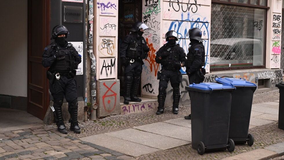 Vermummte Beamte vor einem Haus an der Wolfgang-Heinze-Straße.