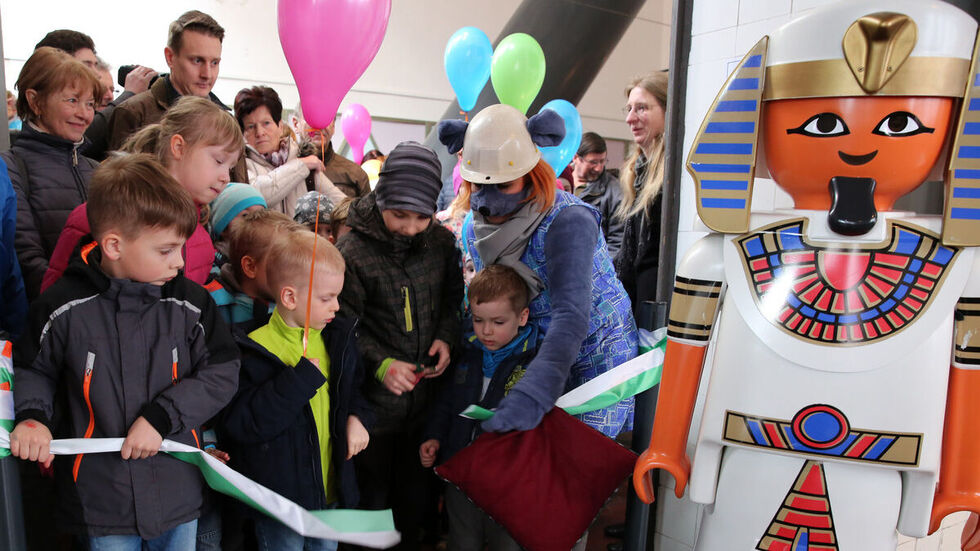 Kinder schneiden das Band zur Ausstellung durch.